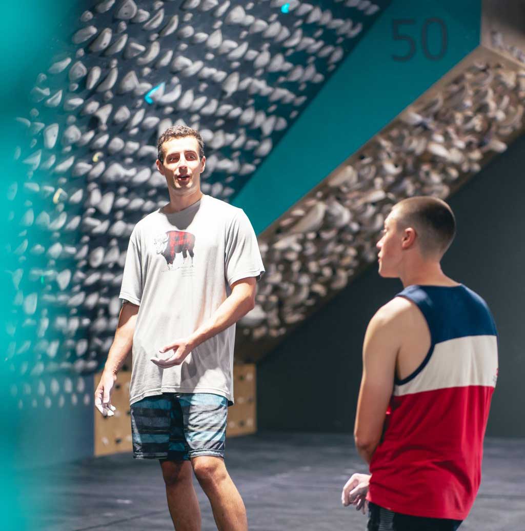 Two climbers discussing beta beneath the Kilter Board during a training session