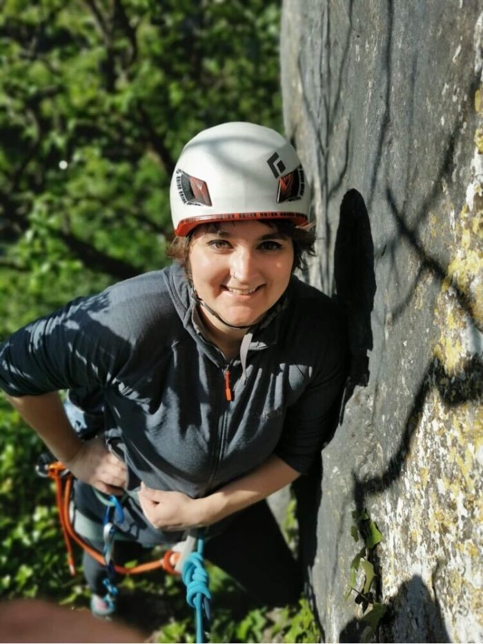 Clara smiling as she pauses for a moment during a trad ascent (with a beautifully tied Figure of 8 knot, it has to be said)!