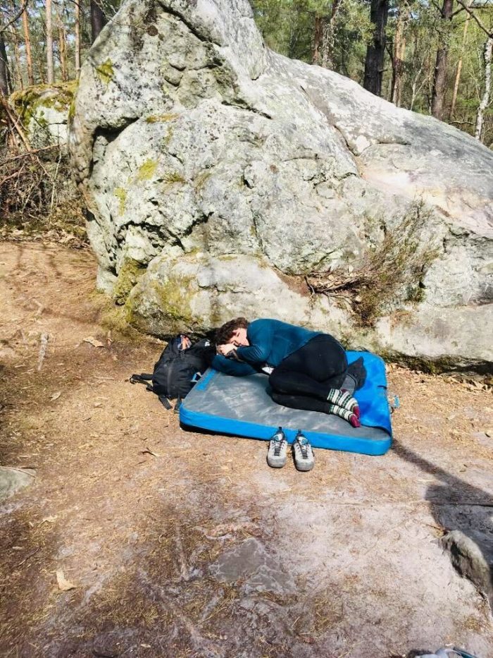 Clara resting her eyes on a boulder mat at the crag. 